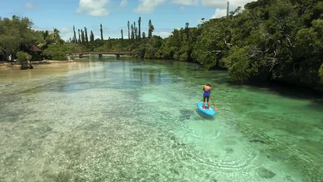 Woman on a paddle board in a beautiful water channel on the Isle of Pines New Caledonia - aerial