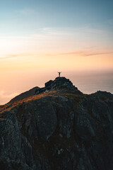 Man climber on the top of mountain traveling in Norway alone enjoying aerial view hiking outdoor traveler raised hands healthy lifestyle adventure vacations exploring Lofoten islands freedom concept - 737876221