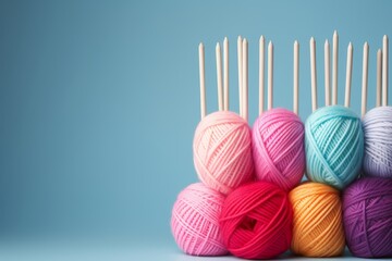 Colorful yarn and knitting needles composition on blue background for crafting concept. Copy space