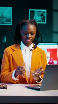 Vertical Video Portrait of african american student putting glasses on and working on english essays at home, reading academic databases for additional resources. Young woman studying at university