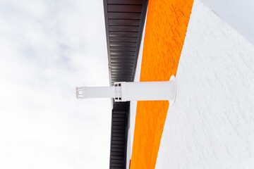 A white and orange building with a white gutter on the side