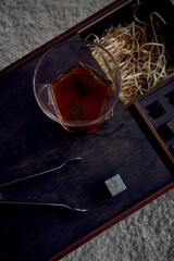 whiskey with tongs, stone cubes, wooden box and wheat on carpet