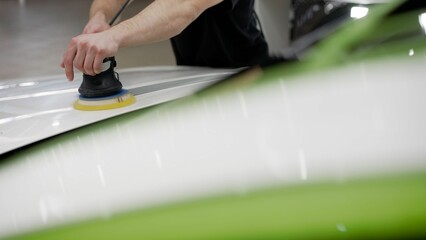 Car painter working with grinding tools, polishing parts, car painting services, car repair after an accident. Machine grinding process, car detailing.