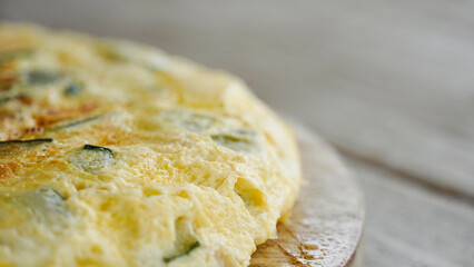 Close up zucchini omelet on white wooden table with space for text.
