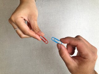 Hands holding colorful Paper clip for paper documents in the office. Office essential tools for...
