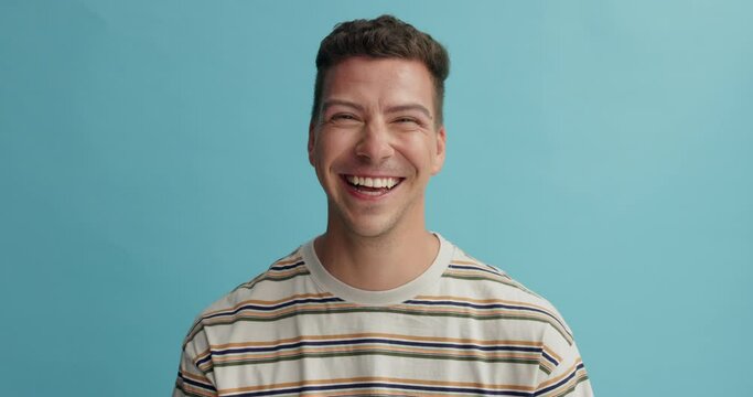 Man, face and happy in fashion with studio, laugh or excited with trendy style by blue background. Person, model or guy with t shirt, clothes or comic smile in portrait with expression for funny joke