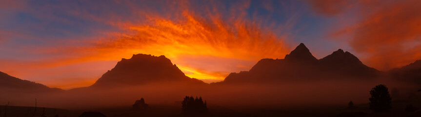 High resolution stitched alpine summer sunrise panorama with a foggy view of Mount Zugspitze at...