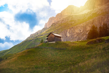 Wooden house among green meadows in Dolomite alps, Italy in summer