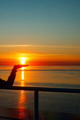 Girl silhouette with sun on the palm in magical sunset over the Gulf of Finland, Baltic sea.