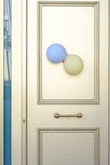 Door of a house with two blue and yellow balloons, indicating a festive event.