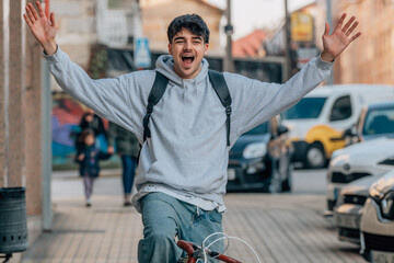 young urban outfit riding a bicycle celebrating excited