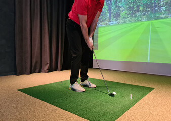Golf player playing golf indoors on golf simulator closeup