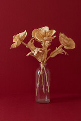 A glass vase with a bouquet of flowers made from straw on the red background. Straw weaving