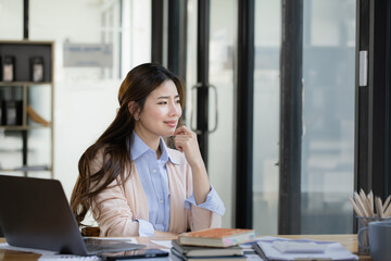 Happy asian young businesswoman using laptop with business finance chart sitting at office working space, Business finance and accounting woman concept.