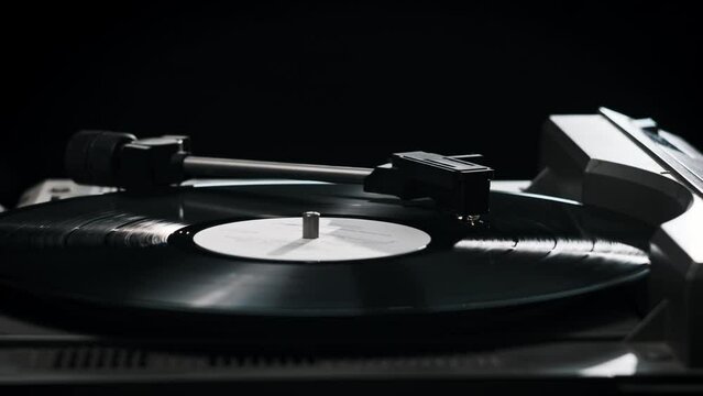 Vintage vinyl record rotates on the retro turntable, needle touches the vinyl close-up. Hand turns on a vintage vinyl record. Stylus drops to a records. Spinning vinyl record. Playing retro music