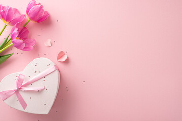Perfect feminine celebration setting. Overhead shot of a heart-adorned present box, glitter, small hearts, and natural tulips on a soft pink surface, leaving space for text or promotions