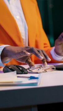 Vertical Video Portrait of african american student putting glasses on and working on english essays at home, reading academic databases for additional resources. Young woman studying at university