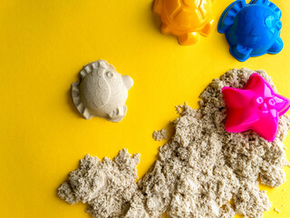 Beige kinetic sand for kids on yellow background, development and play at home with colorful...