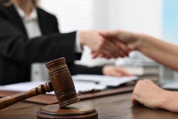 Lawyer shaking hands with client in office, focus on gavel