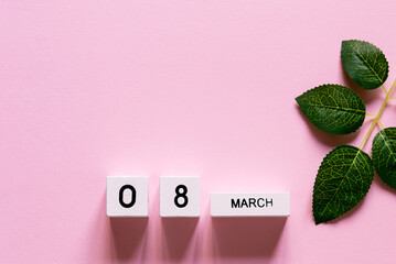Women's day composition. 8 march wooden calendar with a branch of green leaves on the pink...