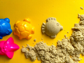 Beige kinetic sand for kids on yellow background, development and play at home with colorful...