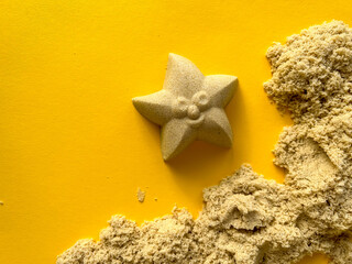 Beige kinetic sand for kids on yellow background, development and play at home with colorful...