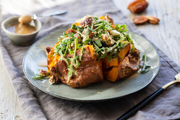 Baked sweet potato with rocker, dates, pecans, feta and tahini dressing