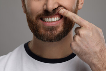 Obraz premium Man showing his healthy teeth and gums on grey background, closeup
