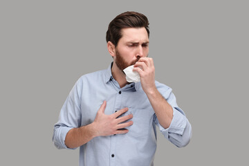 Sick man with tissue coughing on light grey background