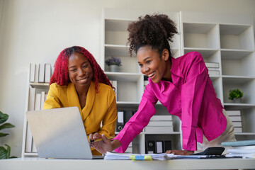 Two businesswoman African American working together using laptop and talking about a business...