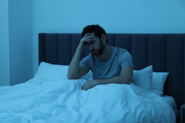 Man suffering from headache in bed at night