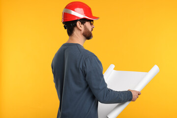Architect in hard hat with draft on orange background