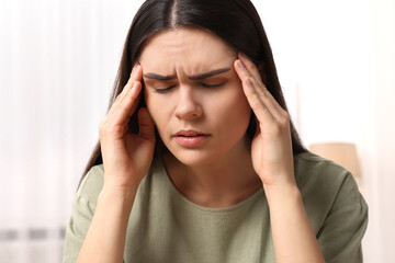 Sad woman suffering from headache at home