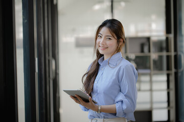 Happy asian young businesswoman using digital tablet standing in office  working space.