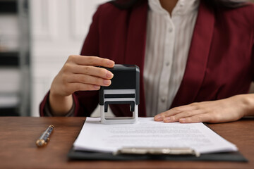 Notary stamping document at table in office, closeup