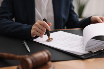 Notary sealing document at table in office, closeup