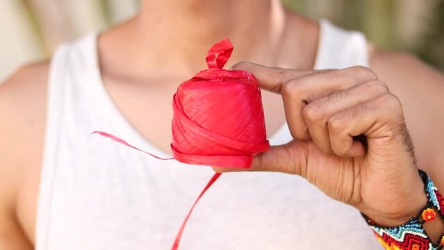 Artisan Unwinding Red Raffia for Craft. Close-Up Unrecognisable Man Handcrafts