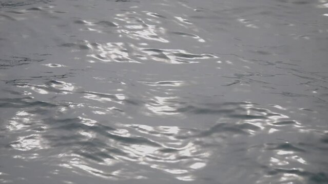 Shimmering sunlight on undulating swirling hypnotic waves of freshwater lake