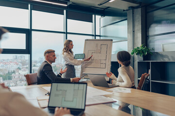 Confident young businesswoman giving a presentation during a meeting with her colleagues