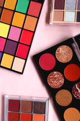Various colorful eyeshadow palettes on bright pink background. Flat lay.