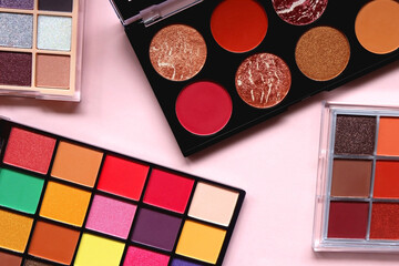 Various colorful eyeshadow palettes on bright pink background. Flat lay.