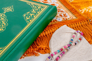 Quran,Men's skullcap ,muslim rosary beads seen on prayer mat.Ramadan Concept.