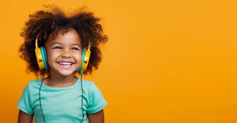 Foto op Plexiglas A happy African girl, wearing headphones and listening to music with curly hair to celebrate. © Danko
