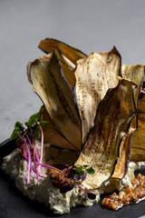 Dried eggplant slices served as appetizer on black plate