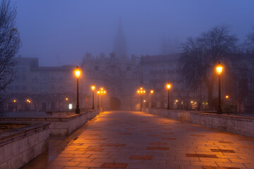 Santa María bridge and arch in the city of Burgos at night in the mist. Castilla y Leon, Spain.
