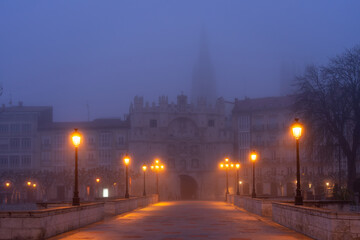 Santa María bridge and arch in the city of Burgos at night in the mist. Castilla y Leon, Spain.