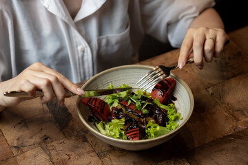 Woman eating salad in a restaurant, close-up. Healthy food. chicken liver salad