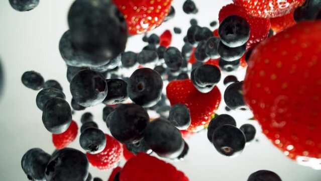 Super Slow Motion of Falling and Rotating Berries on White Background, Top View. Filmed on High Speed Cinema Camera, 1000 fps. Camera Placed on High Speed Cine Bot with Rotating Camera.