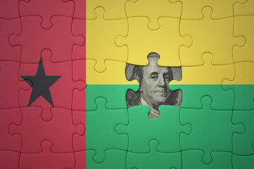 puzzle with the national flag of guinea bissau and usa dollar banknote. finance concept