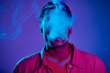 portrait of african american man exhaling smoke against blue background with purple lighting, gen z